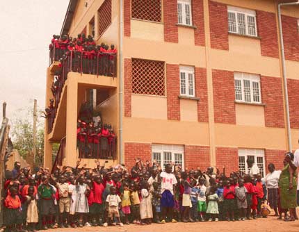 Excited students stand outside the new Meeting Point Kampala School building.