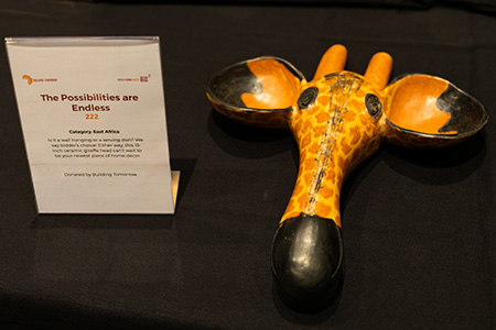 A key bowl in the shape of a giraffe head sits on a silent auction table