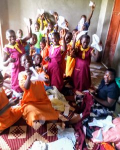 Girls at the Nawankofu Building Tomorrow Academy display the materials used to make the reusable sanitary pads, including the stencils used to trace the shapes of the sanitary pads on cloth. Each pad takes about 20-30 minutes to complete.